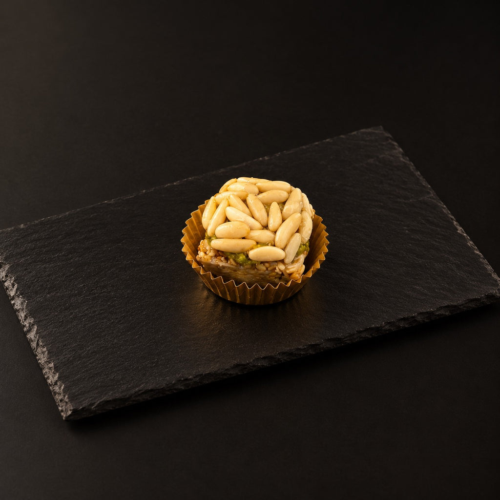 Mignardise en forme de pyramide couverte de pignons, en caissette dorée
